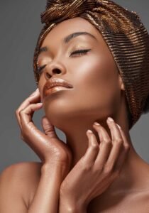 Close-up beauty portrait of a black woman with glowing skin, eyes closed, wearing a patterned headwrap