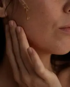 An unedited close-up of a model applying serum onto skin