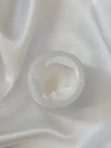 cream in a jar on a white soft satin cloth