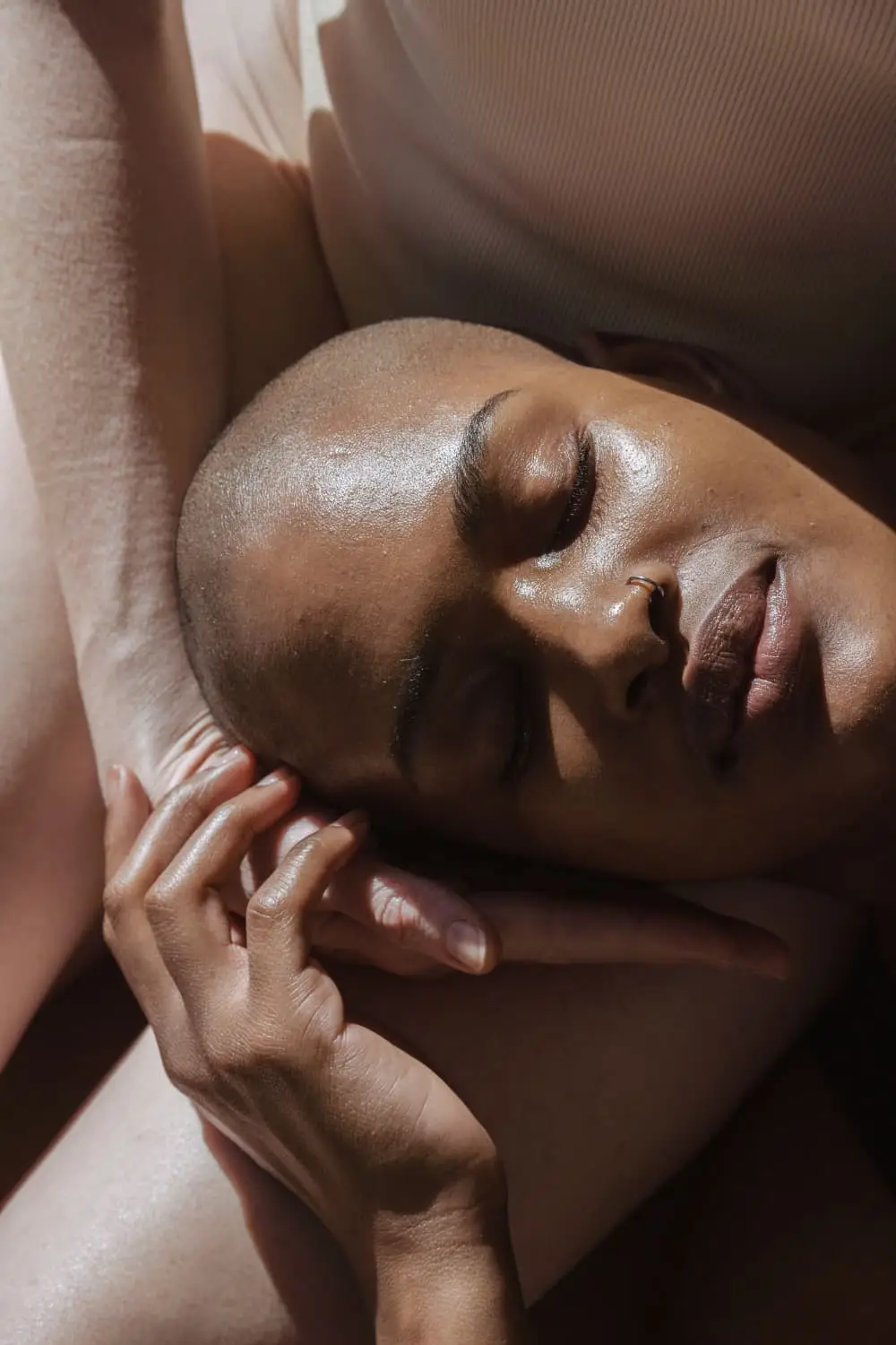 model resting her head on another model's thigh. her hand wrapping the model's face like a support whilst the model relaxes revealing the essence of 3 centimetres a second: the hidden science of touch, rest & the private self