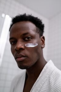 African man in bath robe with a cream smear on his face